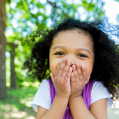 Happy young girl covering her mouth with her hands