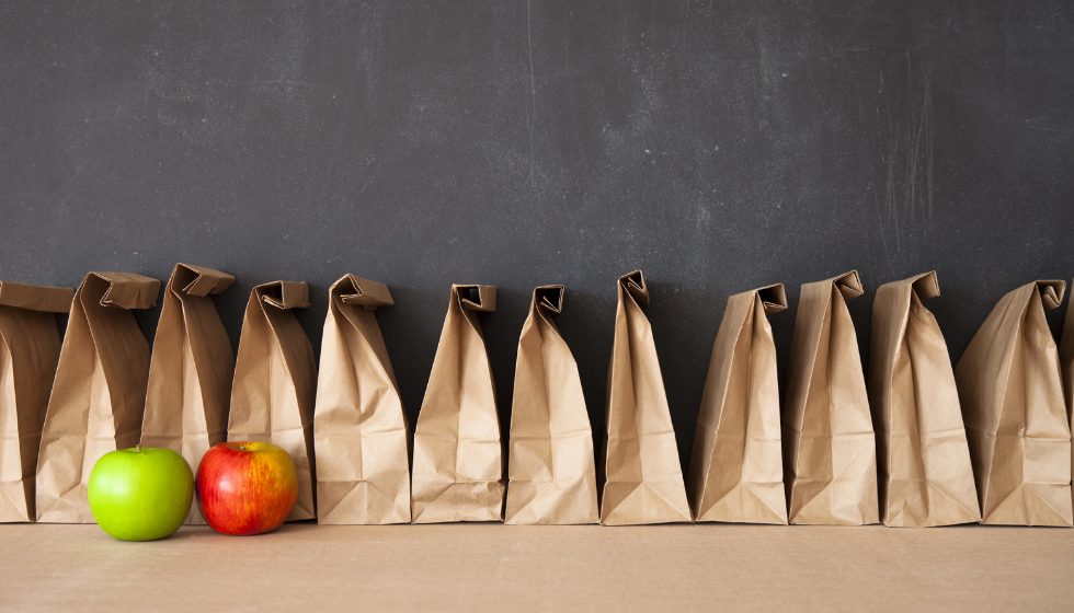 Row of lunch bags with two apples in front