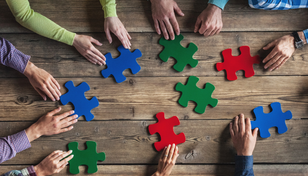 Hands of people assembling large puzzle pieces