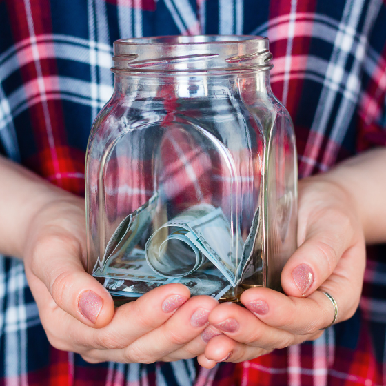 Hands holding a jar with some cash currency inside